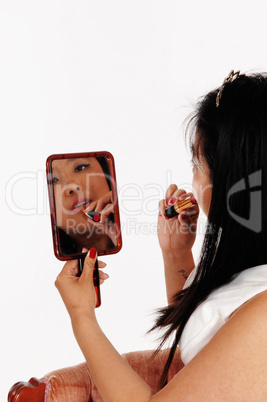 Chinese woman fixing her lipstick holding a mirror