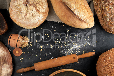 baked different loaves of bread on a black background