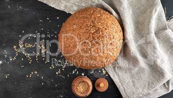 baked round rye bread with sunflower seeds on a beige textile na