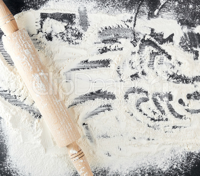 scattered white wheat flour and wooden rolling pin