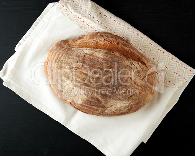 baked oval rye bread on a wooden black board
