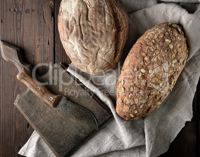 old cutting board, knife and two loaves of brown bread