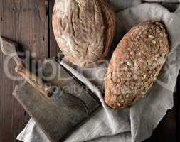 old cutting board, knife and two loaves of brown bread