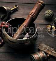 copper singing bowl and a wooden stick on a brown table
