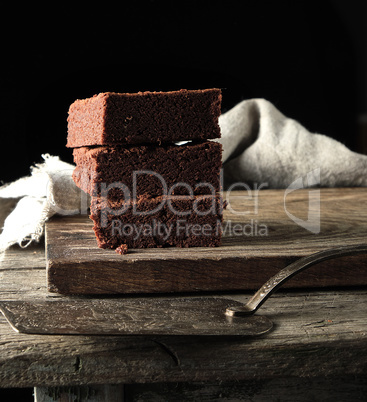 stack of square pieces of baked brown brownie pie on a wooden  b