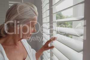 Active senior woman looking through window in a comfortable home