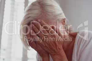 Active senior woman covering face with her hands at home