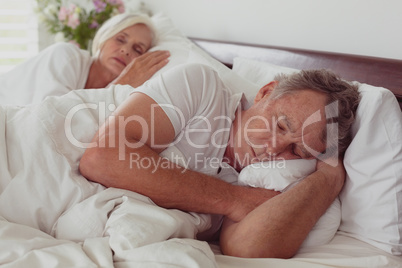 Active senior couple sleeping together in bed in bedroom at comfortable home