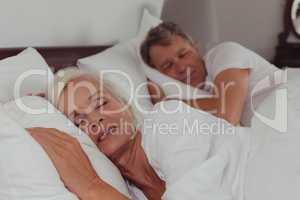 Active senior couple sleeping together in bed in bedroom at comfortable home