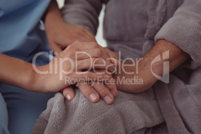 Female doctor consoling active senior man in a comfortable home