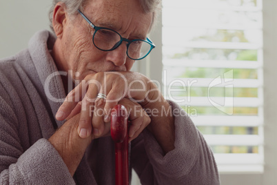Active senior man leaning on walking cane in a comfortable home