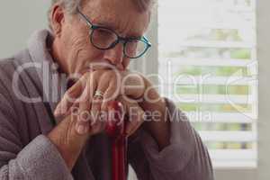 Active senior man leaning on walking cane in a comfortable home