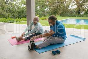 Active senior couple doing stretching exercise in the porch at home