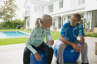 Active senior couple talking with each other after workout in the porch at home
