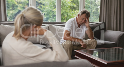 Active senior man with hand on forehead sitting on sofa in a comfortable home