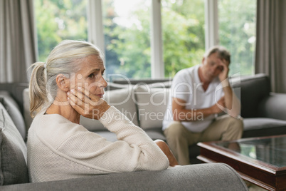 Active senior woman with hand on face sitting on sofa in a comfortable home