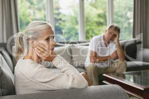 Active senior woman with hand on face sitting on sofa in a comfortable home