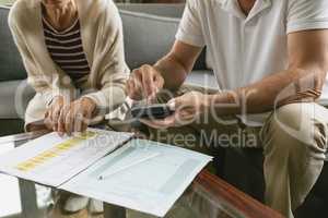 Active senior couple calculating domestic bills on sofa in living room at comfortable home