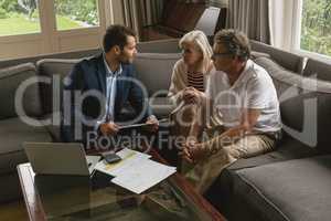 Active senior couple discussing with real estate agent in living room