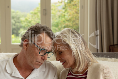 Active senior couple head to head on sofa in a comfortable home