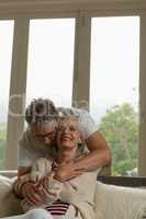 Active senior man embracing senior woman in living room at comfortable home