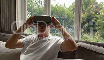 Active senior man using virtual reality headset on sofa in a comfortable home