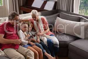 Multi-generation family using digital tablet on sofa in a comfortable home