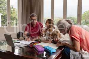 Grandparents helping grandchildren with homework in living room
