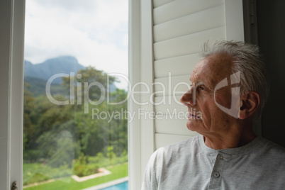 Active senior man looking through window in a comfortable home