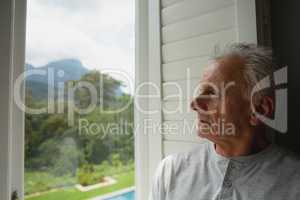 Active senior man looking through window in a comfortable home
