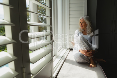 Active senior woman looking through window at home