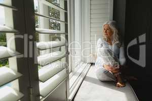 Active senior woman looking through window at home