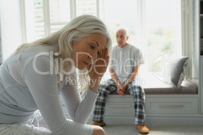 Active senior couple ignoring each other in bedroom Active senior couple ignoring each other in bedroom