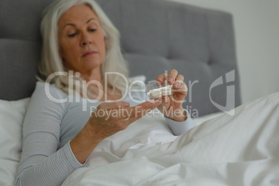 Active senior woman taking medicine in bedroom