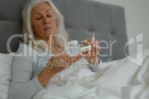 Active senior woman taking medicine in bedroom