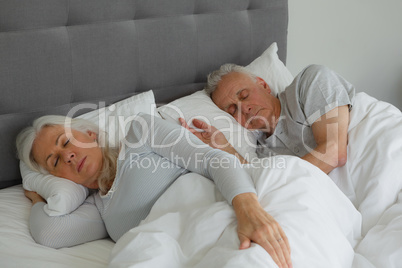 Active senior couple sleeping together in bed in bedroom