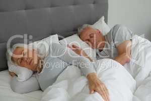 Active senior couple sleeping together in bed in bedroom