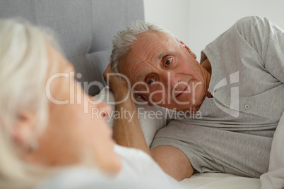 Senior man talking with senior woman while sleeping in bedroom