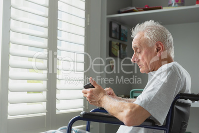 Active senior man in wheelchair using mobile phone at home