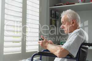 Active senior man in wheelchair using mobile phone at home