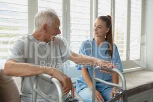 Female doctor interacting with active senior man on window seat