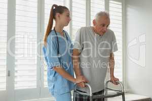 Female doctor helping active senior man to walk with walker