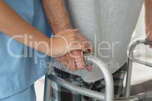 Female doctor helping active senior man to walk with walker at home