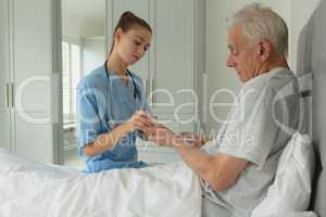 Female doctor giving medicine to active senior patient in bedroom