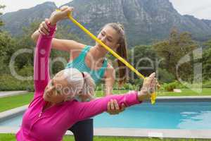 Female trainer assisting active senior woman to exercise with resistance band
