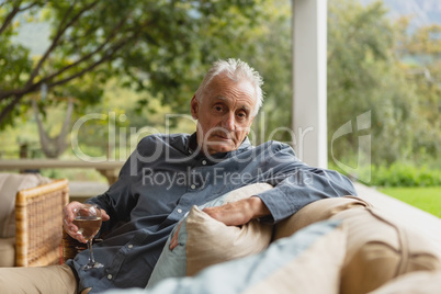 Active senior man having champagne in the porch at home