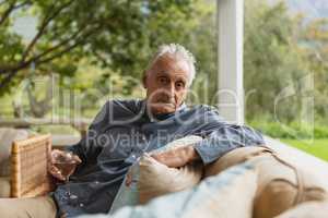 Active senior man having champagne in the porch at home