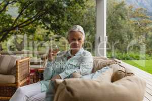 Active senior woman having champagne in the porch at home