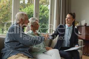 Active senior man shaking hands with real estate agent in living room