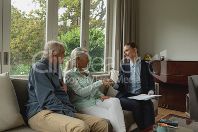 Active senior woman shaking hands with real estate agent in living room